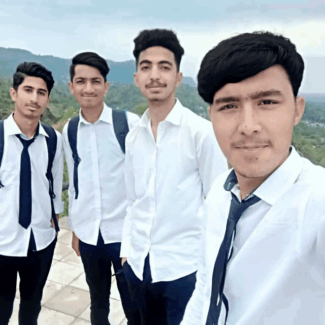 four young men in white shirts and ties pose for a photo