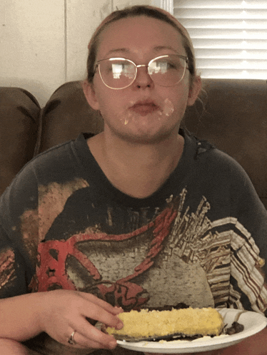 a girl wearing glasses and a ninja turtle shirt eating corn on the cob