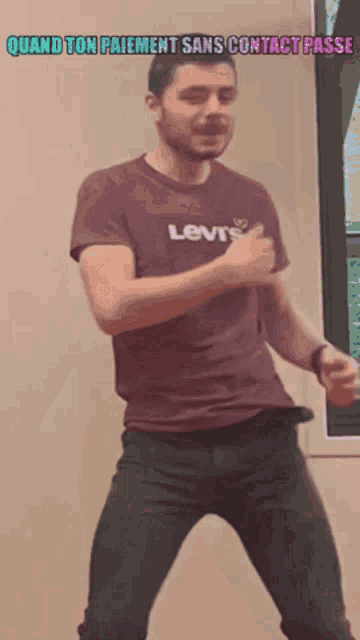 a man in a levi 's shirt is dancing in front of a window