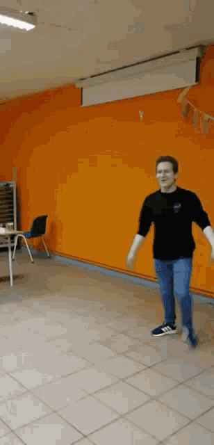 a man is standing in front of an orange wall
