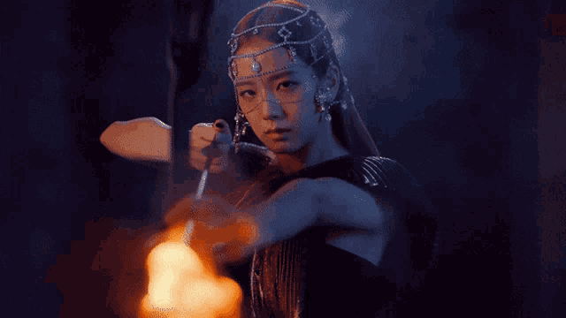 a woman in a black dress is holding a fire