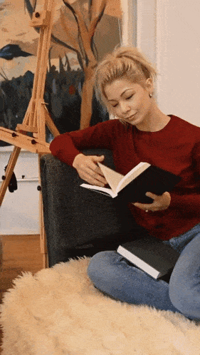 a woman sitting on the floor reading a book