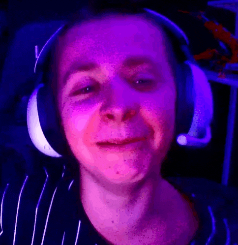 a man wearing headphones is making a funny face in a purple light .