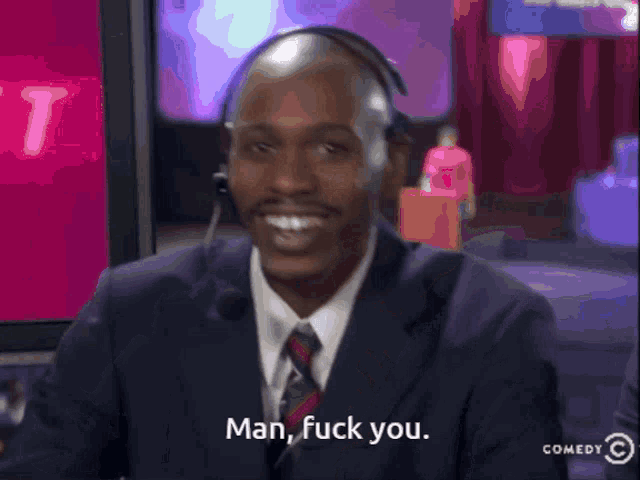 a man in a suit and tie with a headset says man fuck you
