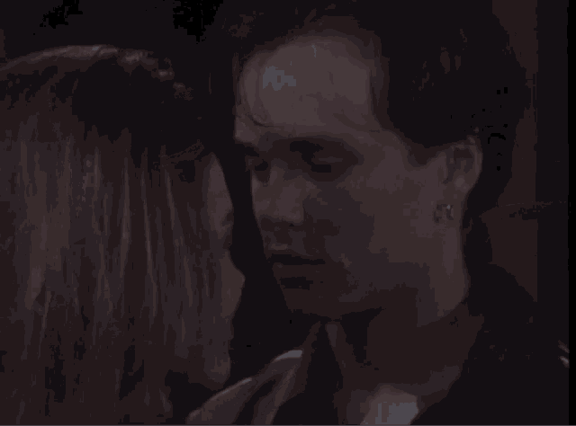 a man and a woman are kissing in a dark room with their eyes closed