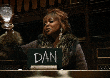 a woman in a fur coat is holding a glass and a sign that says dan