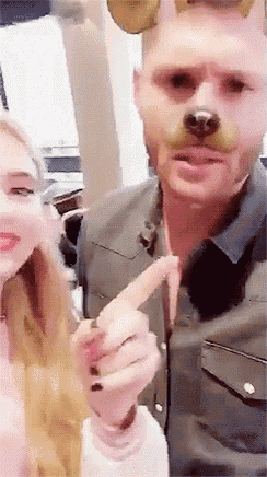a man is wearing a dog mask and a woman is pointing at him .