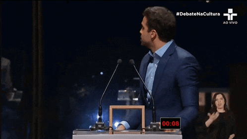 a man giving another man a high five in front of a podium that says debate na cultura on the bottom