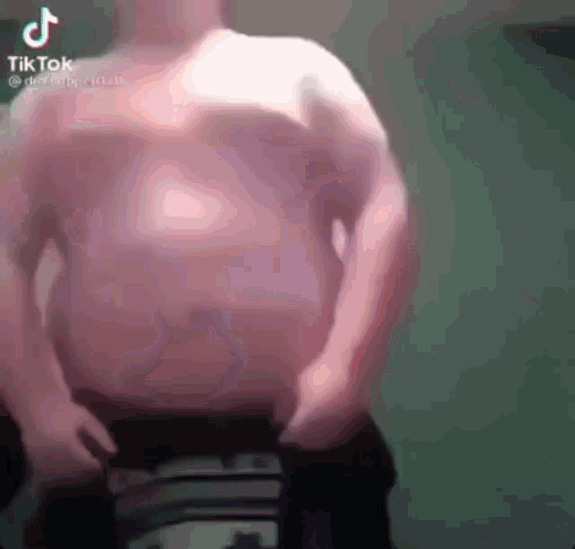 a man without a shirt is standing in a room with his hands on his hips .