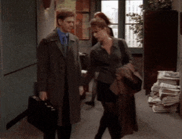 a man and a woman are walking down a hallway holding hands