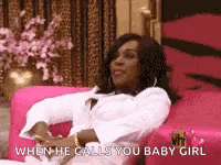 a woman is sitting on a pink couch and talking to a man .