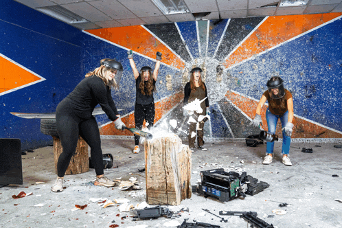 a group of women are playing a game of axe throwing while wearing helmets
