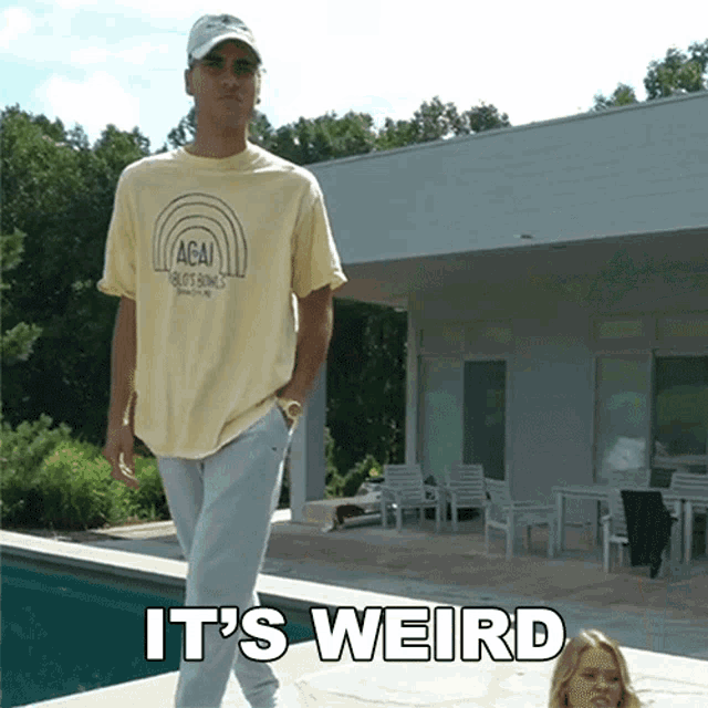 a man in a yellow acai shirt stands next to a pool