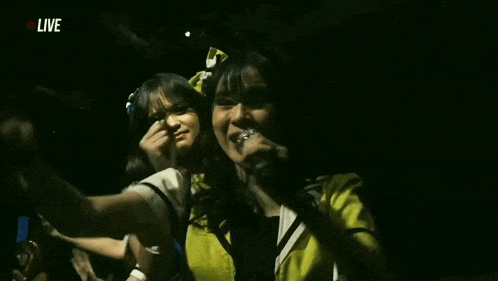 a group of girls are dancing in a dark room while holding microphones .