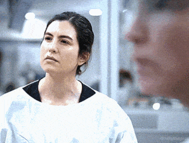 a woman in a lab coat looks at another woman