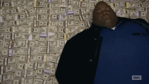 a man is laying on top of a pile of money on the ground .