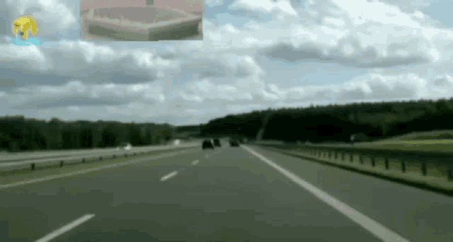 a car is driving down a highway with a picture of a dog in the background .