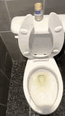a toilet with a bottle of salt on top of it is sitting in a bathroom .