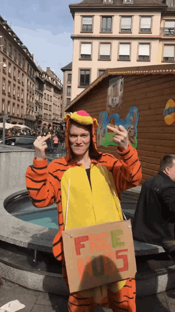 a man dressed in a tiger costume holds a cardboard sign that says free kids
