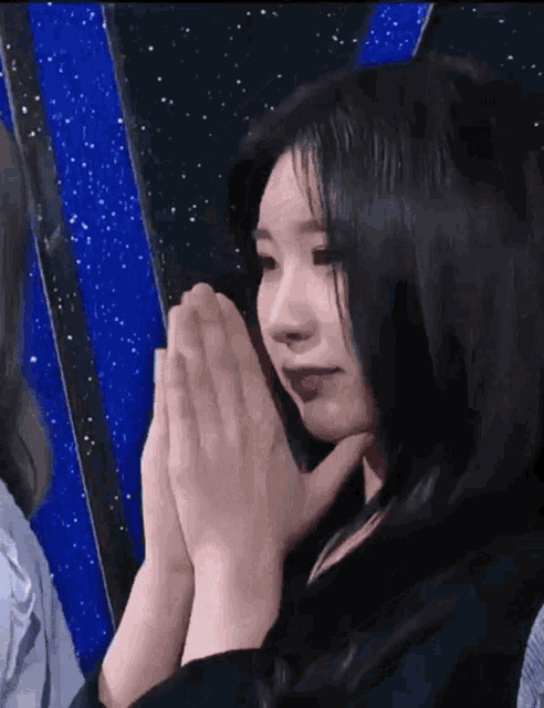 a close up of a woman with her hands folded in prayer