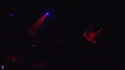 a man sings into a microphone while another man plays a guitar on stage