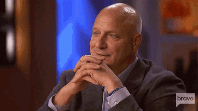 a bald man in a suit is sitting in front of a bravo logo