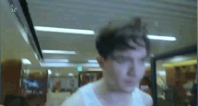 a man in a white shirt is walking down a hallway in a gym .
