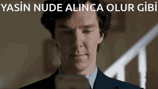a man in a suit looking at a cell phone with the words yasin nude alinca olur gibi written above him