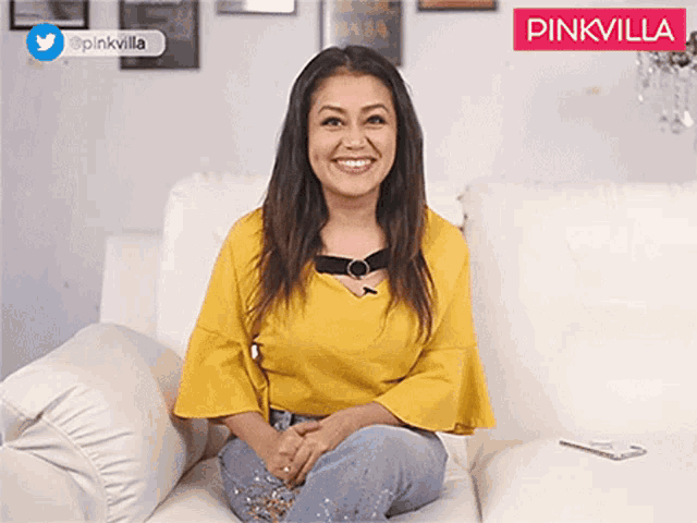 a woman in a yellow shirt is sitting on a white couch smiling