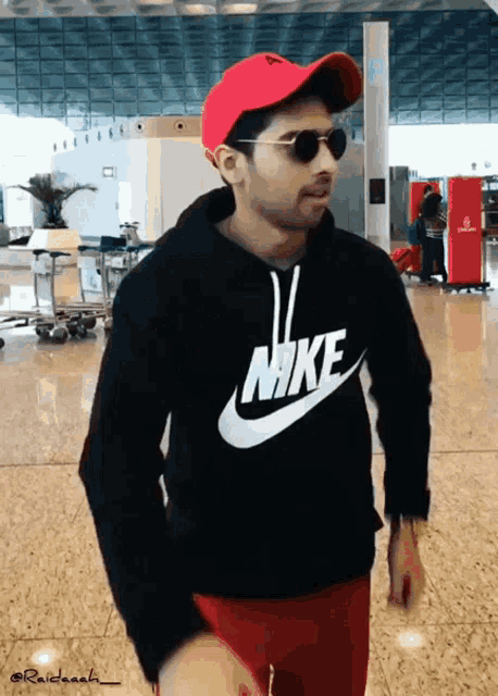 a man wearing a red hat and sunglasses is wearing a nike shirt