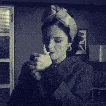 a woman smoking a cigarette in a room with a picture on the wall