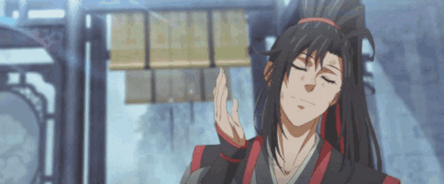 a man with long black hair and a red ribbon in his hair stands with his eyes closed