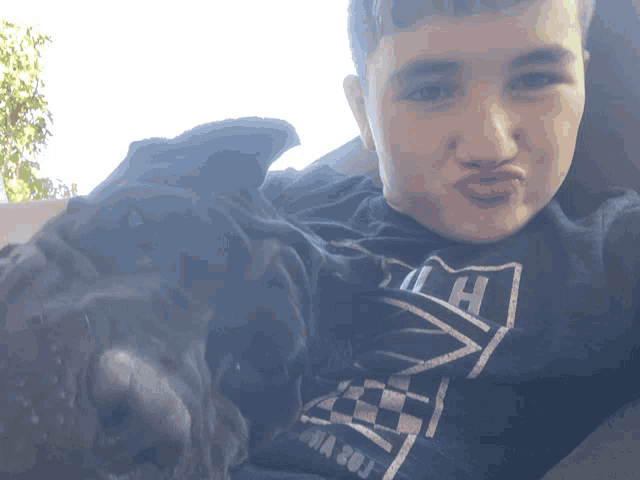 a boy wearing a shirt that says ' la ' on it holds a black dog