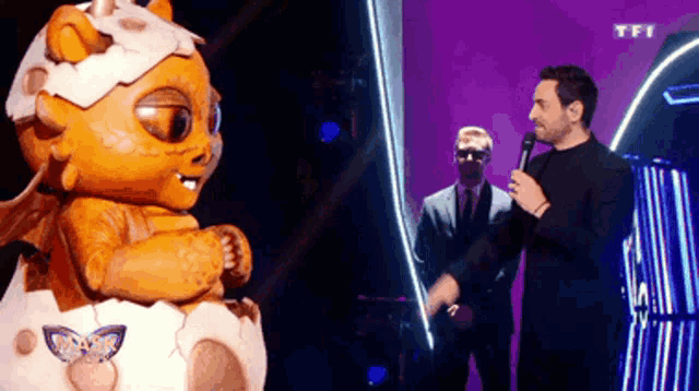 a man is holding a microphone in front of a masked animal that says tfi