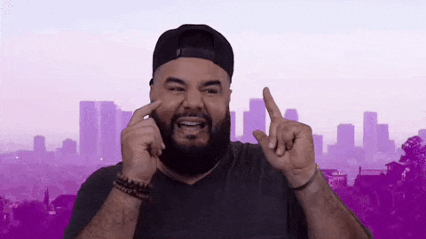 a man with a beard is making a funny face while pointing at his nose .