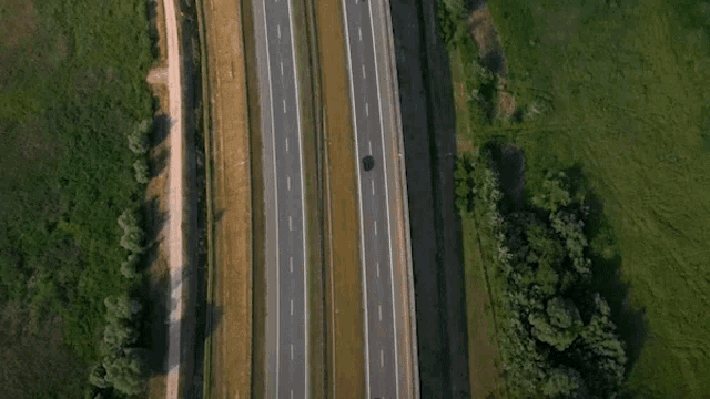 an aerial view of a highway with a car going down it