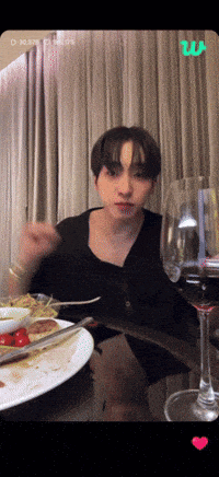 a man sitting at a table with plates of food and a glass of wine