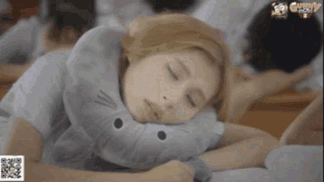 a girl is sleeping on a cat shaped pillow with the word gummy on the bottom right