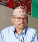 a man wearing a hat and glasses is sitting at a table .