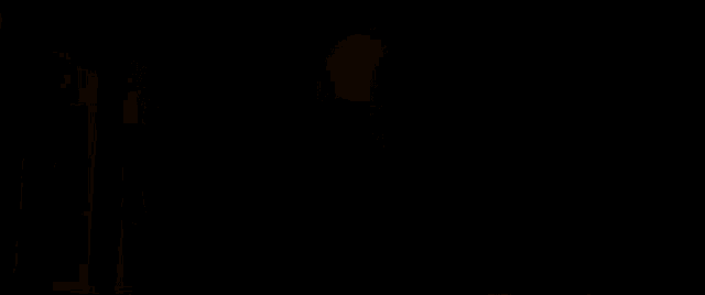 a man is standing in front of a fire behind him