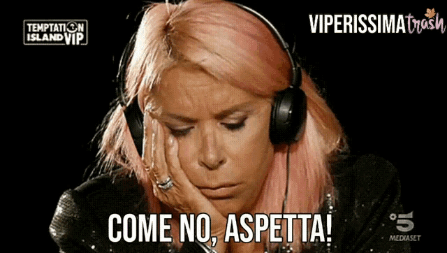 a woman with pink hair wearing headphones says come no aspetta
