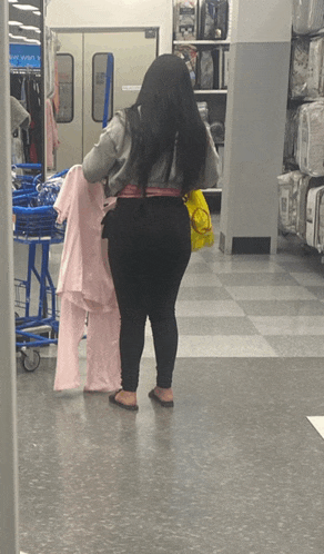 a woman is standing in a store with a sign that says ' clothes ' on it