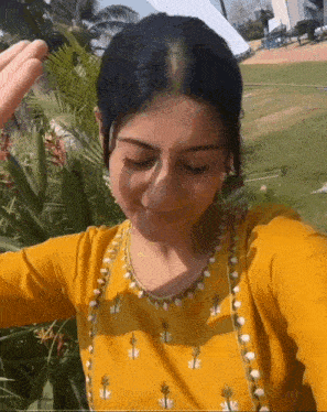 a woman wearing a yellow dress is taking a selfie