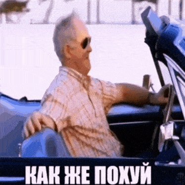 a man wearing sunglasses is driving a car with the words " как же похуй " on the side