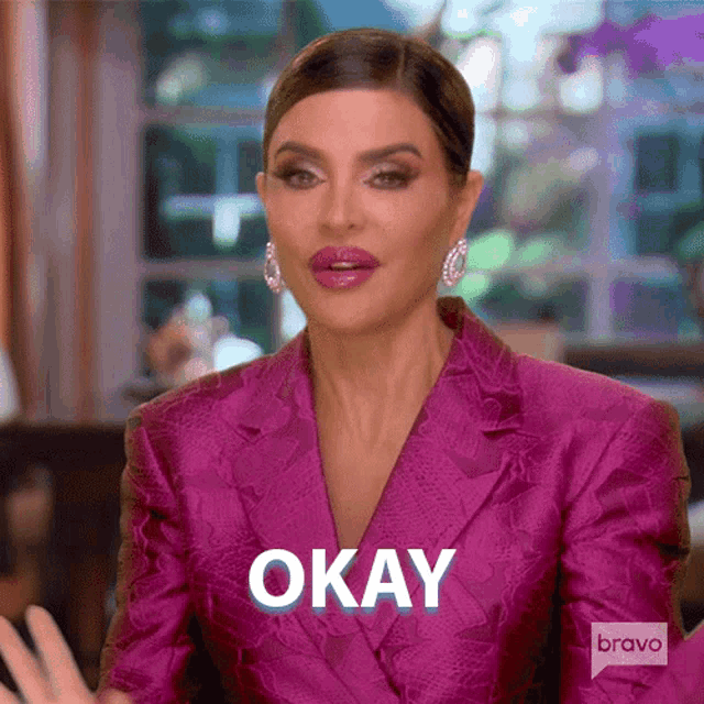 a woman in a pink suit is saying okay with her hands .