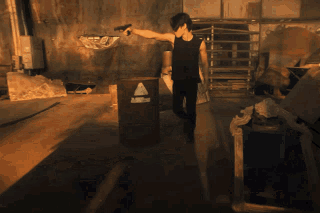 a man in a black tank top stands in a dark room