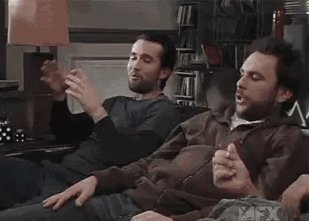 a couple of men are sitting on a couch and one of them is yawning .