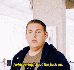 a man is whispering shut the fuck up while wearing a hoodie