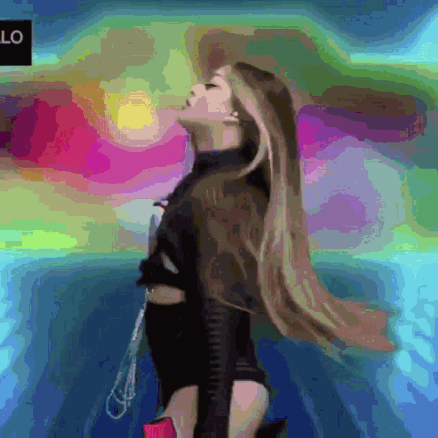 a woman with long hair is standing in front of a colorful background with the word lo on it