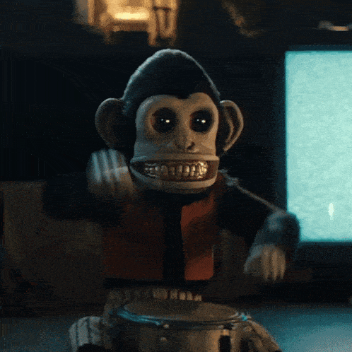 a stuffed monkey is playing a drum in front of a tv screen